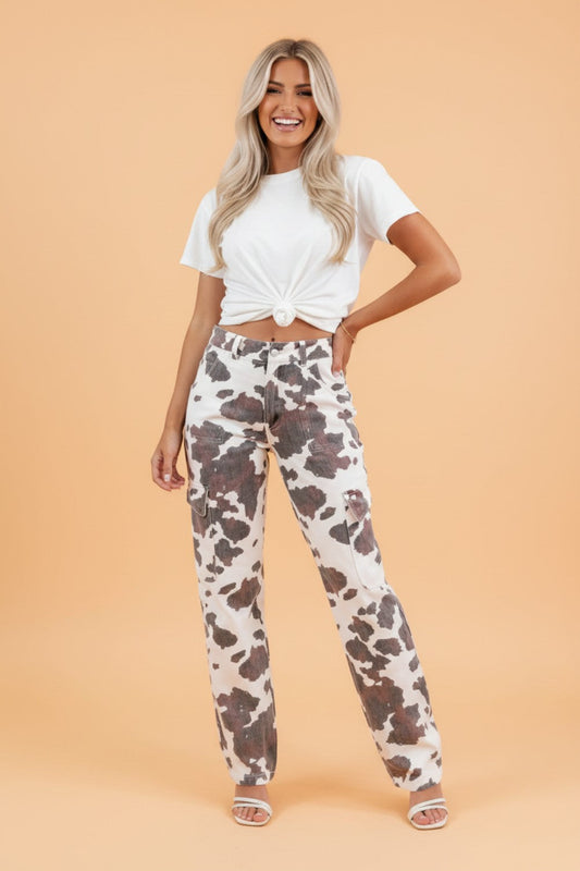 Woman wearing a white t-shirt and cow print pants on a beige background