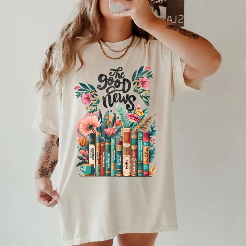 The Good News Floral Bookstack Graphic on Gildan Softstyle Natural Shirt – Graphic Tee, Long Sleeve & Crewneck.