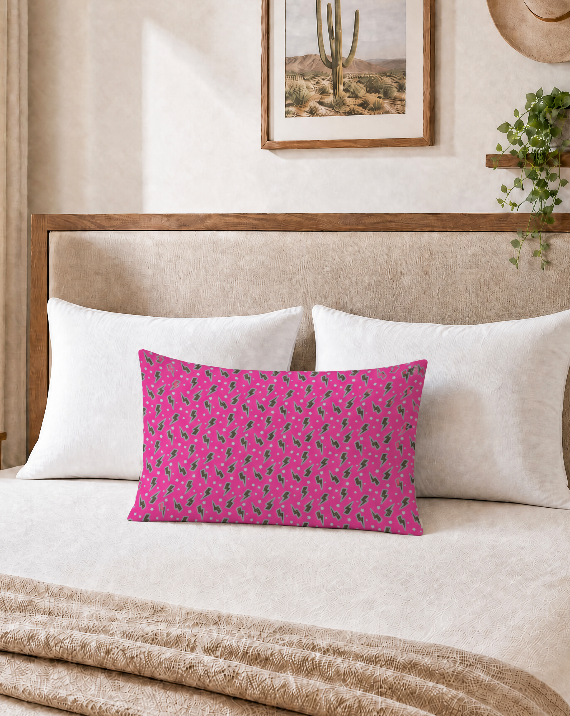 Bedroom with a pink floral pillow on a bed, framed picture on the wall, and lamp on a nightstand.